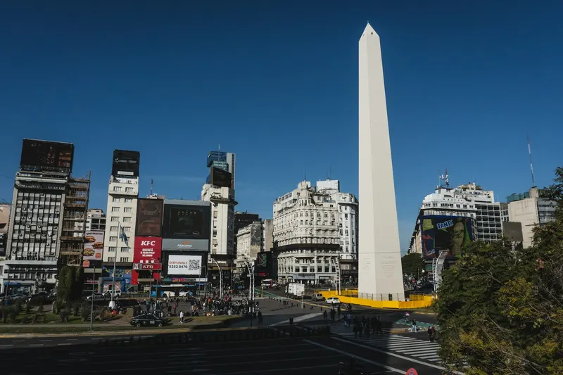 El Obelisco de Buenos Aires rodeado de edificios comerciales y tráfico vehicular durante el día.